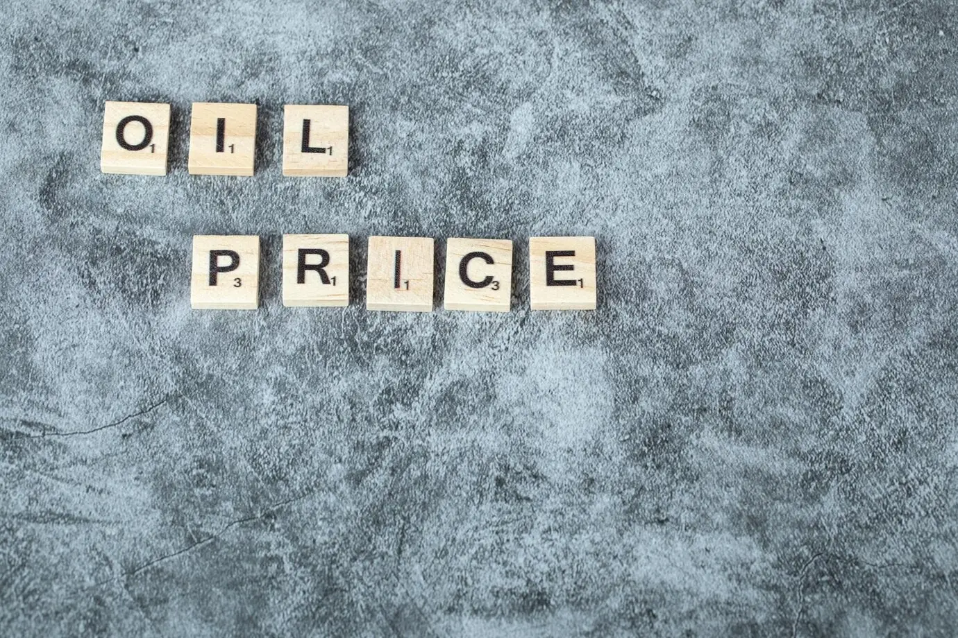 Black letters spelling “Oil price” on wooden dice arranged horizontally. High-quality photo.