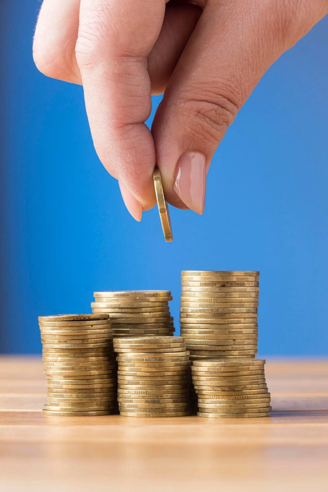 A person putting a coin on top of a pile of coins.