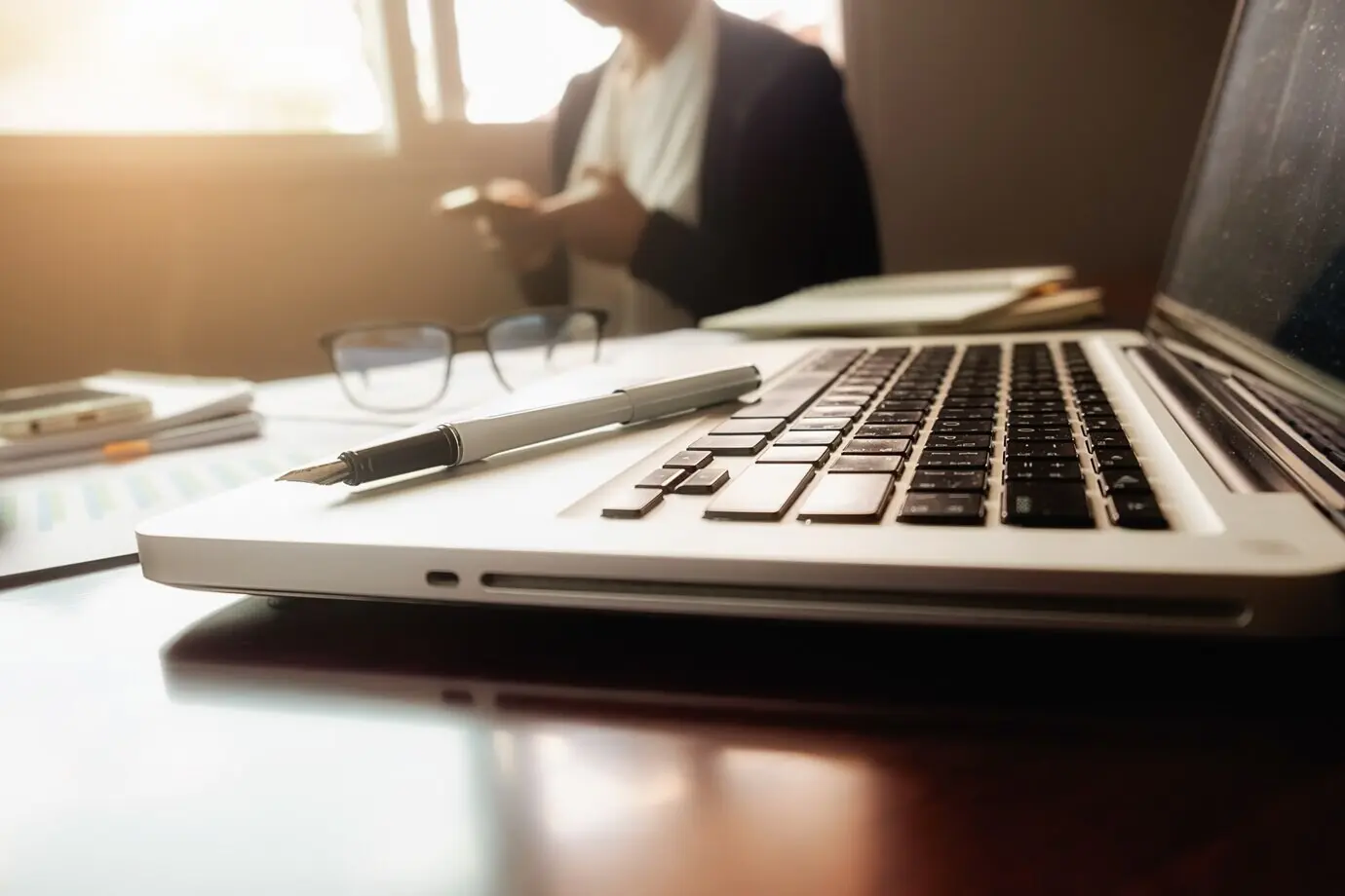 Business concept with copy space: an office desk with a pen in focus, an analysis chart, a computer, a notebook, and a cup of coffee. Vintage tone, retro filter, selective focus.